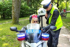 Dziecko siedzi na policyjnym motocyklu, obok stoi policjant.