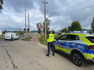 Policjant stoi przy drodze i obserwuje ruch drogowy