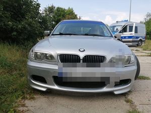 Samochód bmw stoi na poboczu a za nim stoi duży policyjny bus.