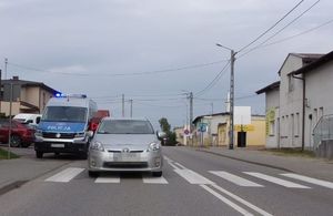 Na pierwszym planie przejście dla pieszych, na nim stojąca toyota a za nią stoi radiowóz