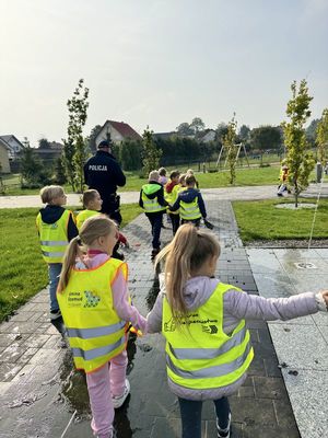 Policjant idzie z dziećmi chodnikiem