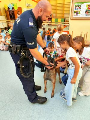 Dzieci podchodzą do policjanta z Luną i głaszczą czworonoga