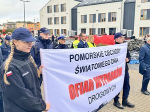 Przemarsz uczestników - czoło kolumny wraz z wywieszonym transparentem informującym o Pomorskich Obchodach Światowego Dnia Pamięci Ofiar Wypadków Drogowych