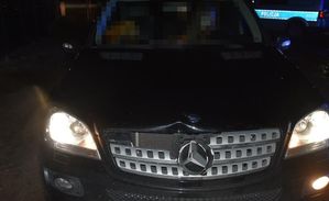 Mercedes który potrącił pieszego z wgnieceniem na masce oraz w tle widoczny policyjny radiowóz