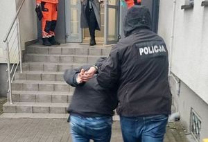 Policjant wprowadza zatrzymanego do komendy