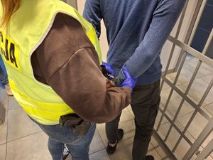 policjantka zakłada kajdanki zatrzymanemu