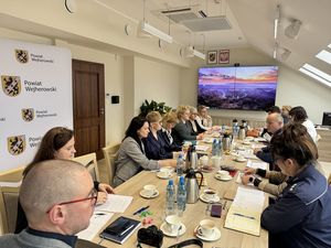 W trakcie spotkania komisji zdrowia psychicznego jej członkowie siedzą przy stole konferencyjnym i rozmawiają