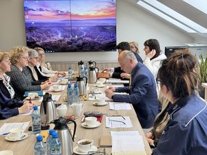 W trakcie spotkania komisji zdrowia psychicznego jej członkowie siedzą przy stole konferencyjnym i rozmawiają