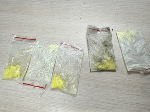 Na biurku leżą narkotyki w małych foliowych woreczkach.
