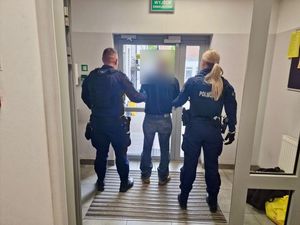 Policjanci wyprowadzają zatrzymanego.