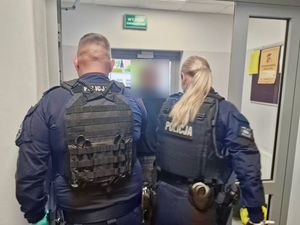Policjanci prowadzą zatrzymanego