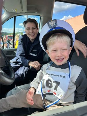 Policjantka z małym chłopcem siedzi w samochodzie. Oboje uśmiechają się do zdjęcia.