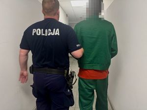 Policjant prowadzi zatrzymanego.