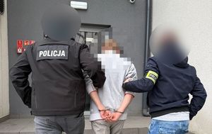 Policjanci wprowadzają zatrzymanego.