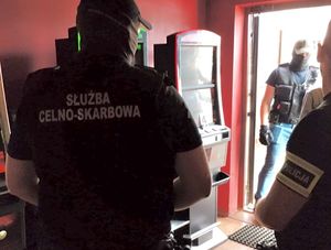 Policjant i funkcjonariusz KAS stoją przy automatach które są zabezpieczane