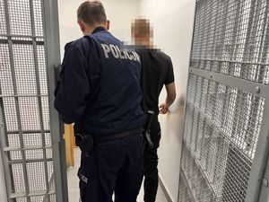 Policjant wprowadza zatrzymanego do celi.
