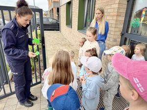 Policjantka rozdaje dzieciom elementy odblaskowe