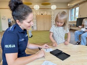 Policjantka wykonuje dzieciom dalktyloskopię