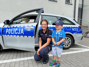 Policjantka pozuje z chłopcem, który jest przebrany za policjanta.