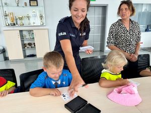 Policjantka wykonuje chłopcu odbitkę linii papilarnych.