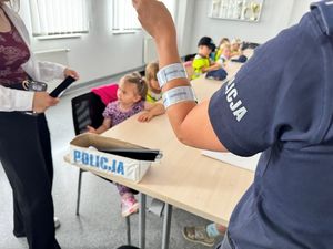 Policjantka prezentuje dzieciom elementy odblaskowe.