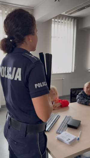 Policjantka prowadzi spotkanie z dziećmi i pokazuje odblaski.