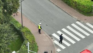 Zdjęcie wykonane dronem, na którym widoczne jest przejście dla pieszych i uczniowie idący do szkoły a także policjanci czuwający nad bezpieczeństwem pieszych.