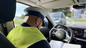 Policjant siedzi w radiowozie i rozpisuje notatnik