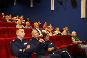Zdjęcie sali kinowej na której siedzą goście i policjanci