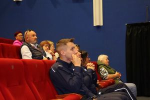 Zdjęcie sali kinowej na której siedzą goście wraz z policjantami