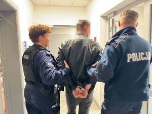 Dwoje policjantów prowadzi zatrzymanego.
