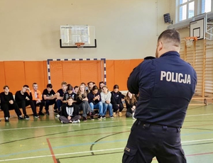 Policjant prowadzi spotkanie z młodzieżą na sali gimnastycznej