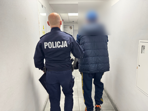 Policjant prowadzi zatrzymanego mężczyznę