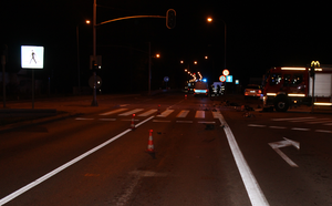 Miejsce zdarzenia drogowego, w tle widać radiowóz, biały samochód - mercedes oraz wóz strażacki