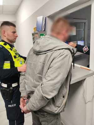 Policjant stoi i trzyma zatrzymanego podczas badania trzeźwości