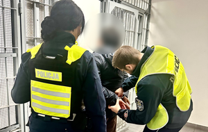 Policjant zdejmuje kajdanki przed celą zatrzymanej.