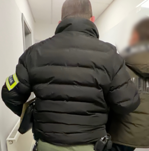 Policjant prowadzi zatrzymanego