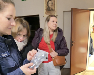 Policjanci rozmawiają z rodzicami i tłumaczą jak niebezpieczne są narkotyki i co przestawiają rekwizyty wystawione na stole.