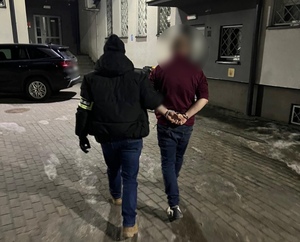 Policjant operacyjny prowadzi zatrzymanego