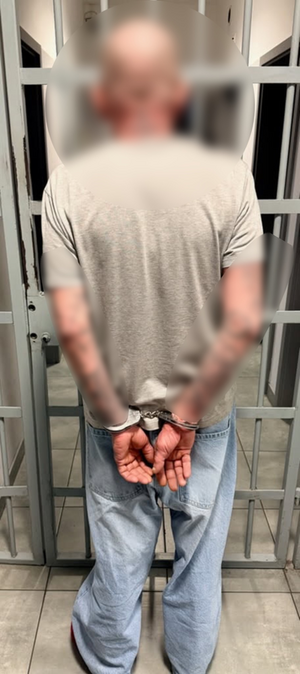 Mężczyzna stoi przed wejściem do pomieszczenia dla osób zatrzymanych.