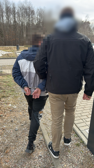 Policjant w ubiorze cywilnym prowadzi zatrzymanego mężczyznę