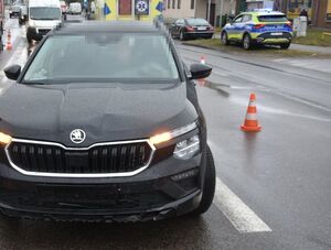 Dwa pojazdy uczestniczące w zdarzeniu, skuter leżący na drodze oraz czarna skoda