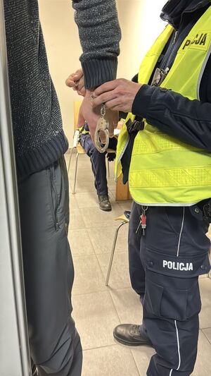 Policjant zakłada kajdanki zatrzymanemu
