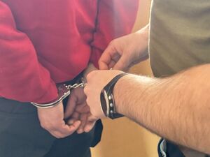 Policjant zakłada kajdanki zatrzymanemu.