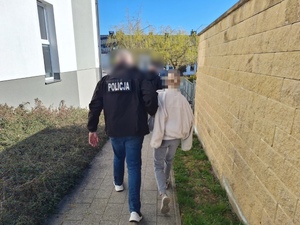 Policjanci prowadzą zatrzymaną kobietę