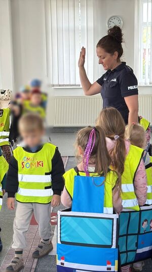 Policjantka oprowadza dzieci po komendzie i rozmawia z nimi o bezpieczeństwie