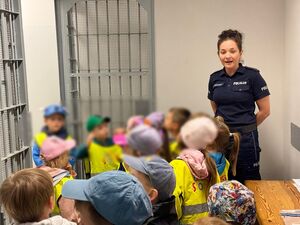 Policjantka oprowadza dzieci po komendzie i rozmawia z nimi o bezpieczeństwie