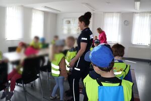 Policjantka oprowadza dzieci po komendzie i rozmawia z nimi o bezpieczeństwie