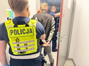Policjant prowadzi zatrzymanego mężczyznę