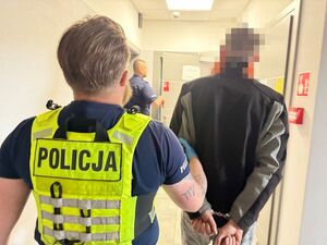 Policjant prowadzi zatrzymanego mężczyznę